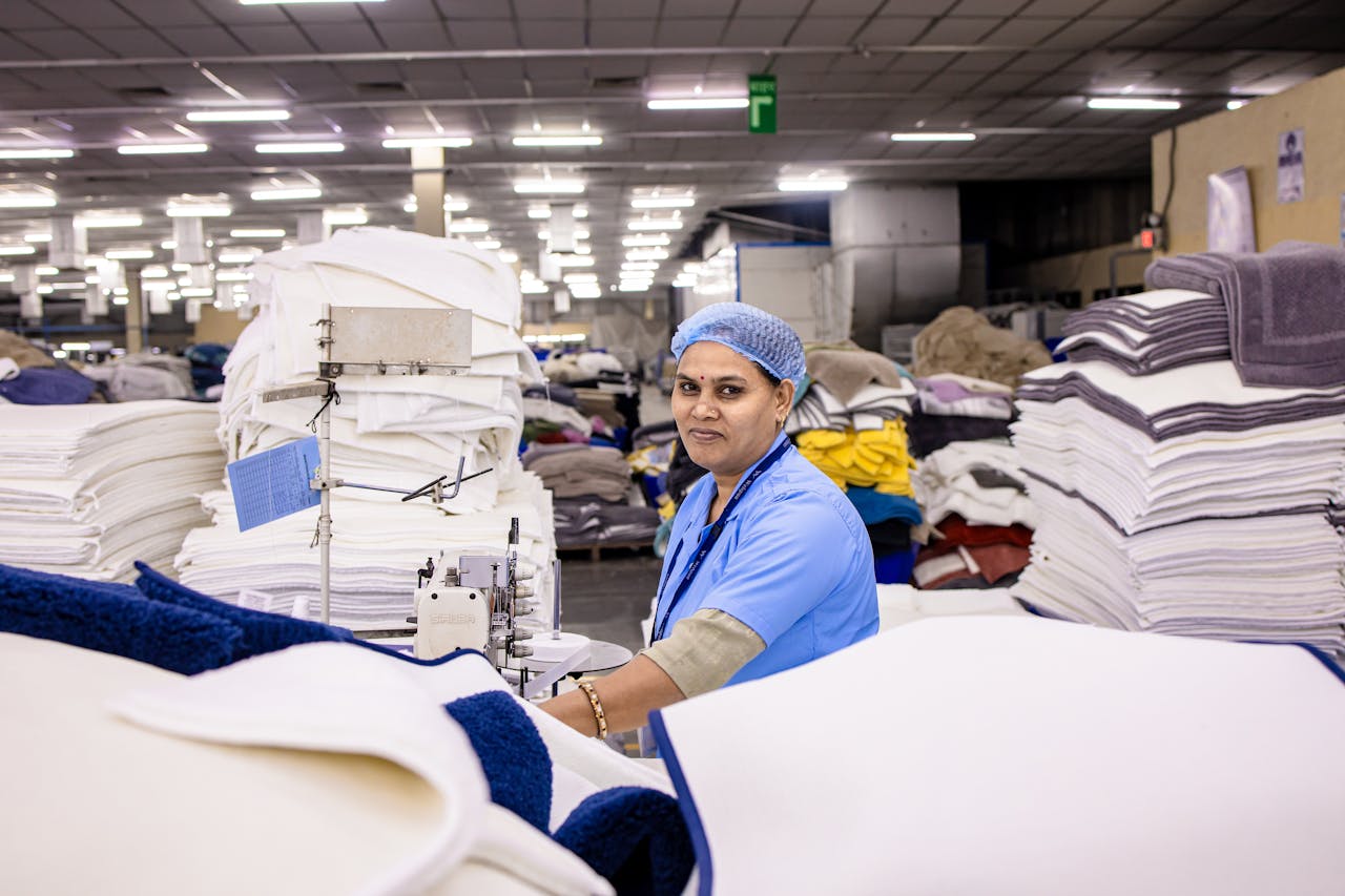 Female textile worker sewing in a busy factory. High quality production environment.
