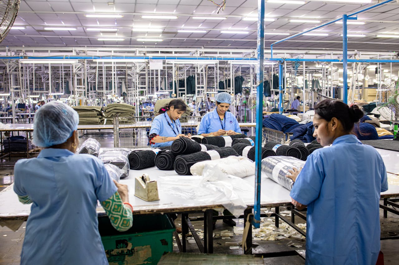Blue-collar workers organize textiles in a busy factory setting.