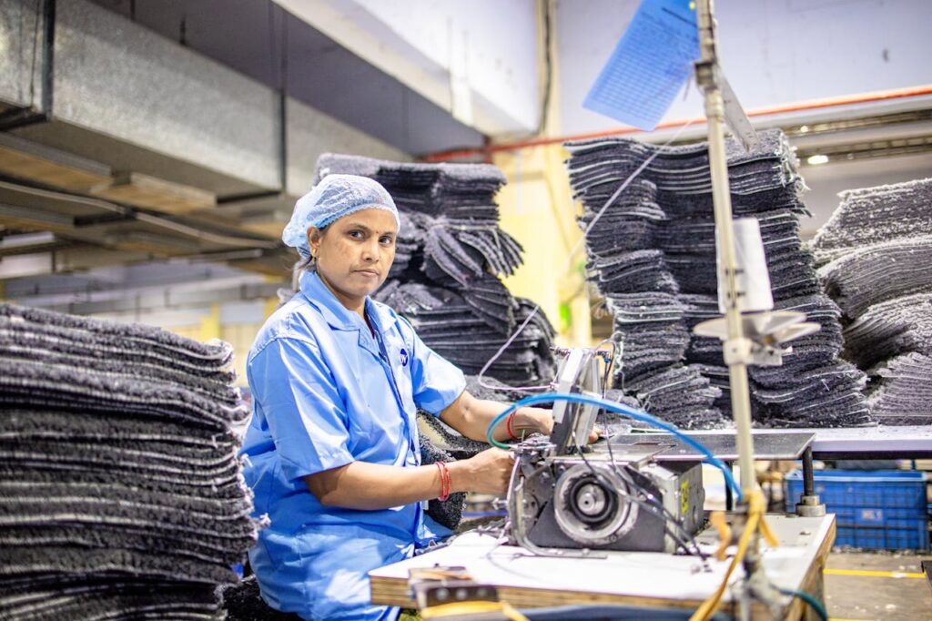 A focused female factory worker at a textile plant in India, working with an industrial sewing machine.