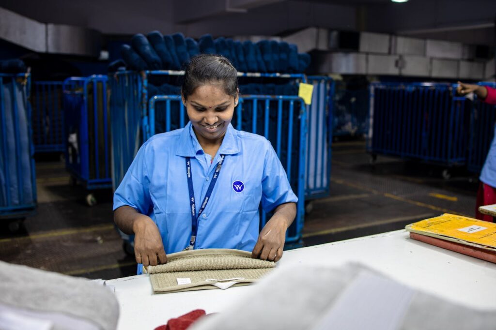 Female factory worker folding textiles on a production line, displaying focus and employment in the textile industry.
